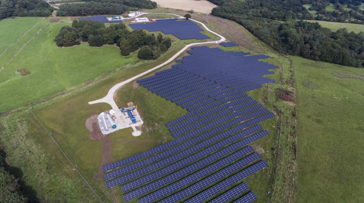 An aerial view of solar panels among grass and trees 