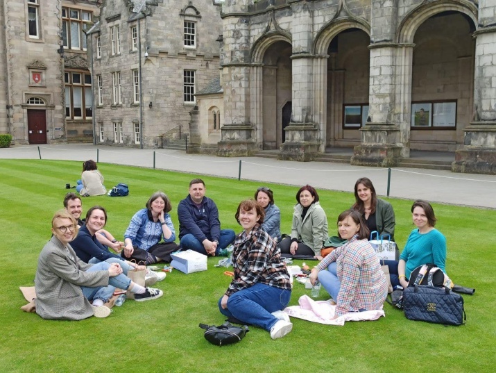 Ostroh Academy students and staff sit on a grass lawn at the University of St Andrews. 