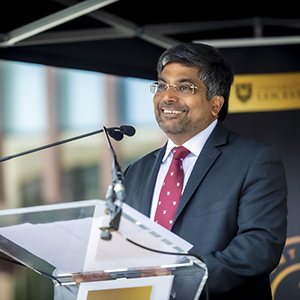 Nishan smiling at a lectern