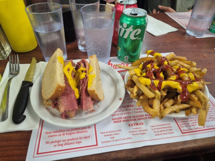 Smoked meat sandwich brimming with fillings, and chips topped with sauces at Schwartz’s