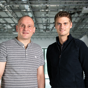 Universal Quantum co-founders standing in a large industrial space. Both are looking towards the camera.