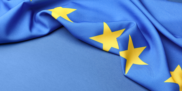A folded European Union flag draped over a blue backdrop 
