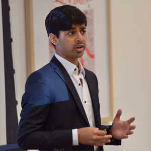Founder of ZNotes, Zubair Junjunia presenting. He wears a navy suit and white collared shirt.