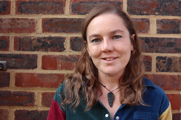 Amy smiling and standing in front of a brick wall