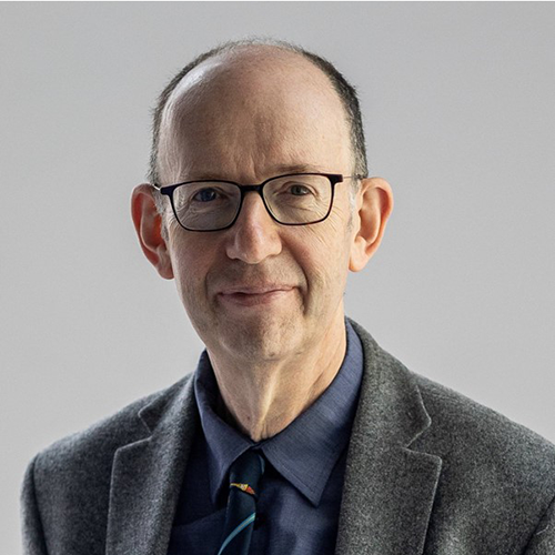Anthony Finklestein smiling in front of a plain background