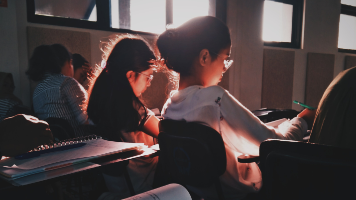 Students learning in a classroom, a bright white sunshine behind them