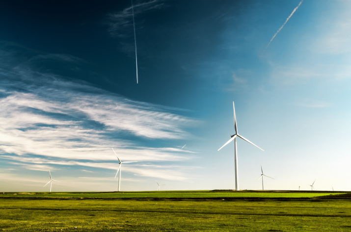 Wind turbines on a field with planes flying overhead