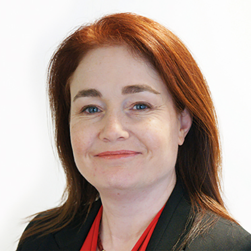Headshot of Debra Gray. She is smiling and wearing a red blouse with black jacket.