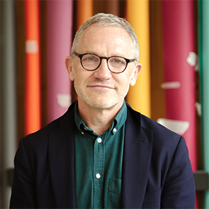 James Purnell smiling against a colourful background.