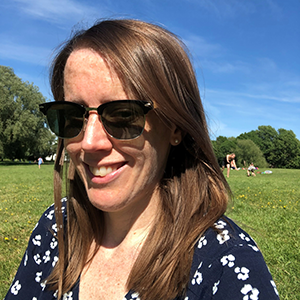 Jo sitting in a park smiling at the camera 