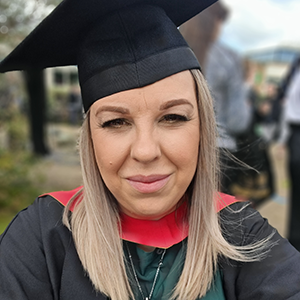 Kerry Edwards smiling at her graduation. She is wearing a graduation gown and mortar board.