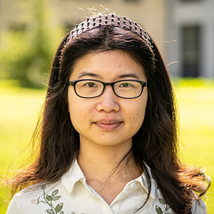 Dr Helen Liang smiling outside with university campus building in the background