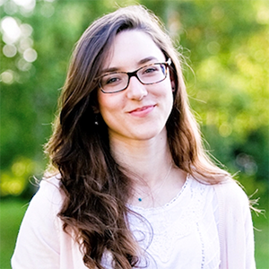 Laura smiling in front of a green leafy background