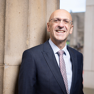 Malcolm Press in a suit looking at the camera and smiling