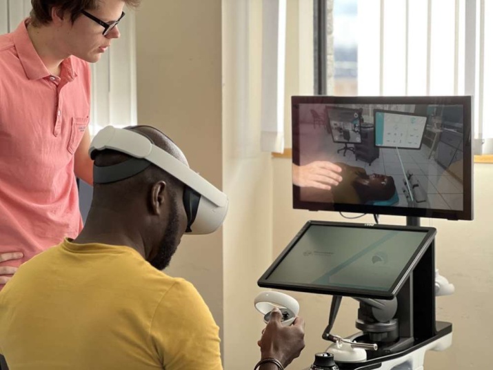A student uses a dental simulator while a professor watches