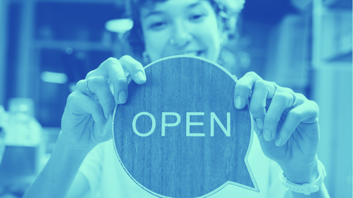 Person putting up an 'Open' sign in the window of their business