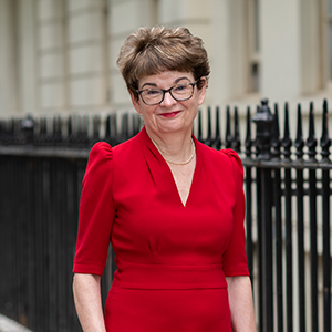 Professor Sally Mapstone DBE smiling outside in Bloomsbury wearing a red dress