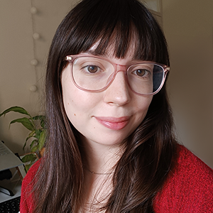 Sofia Henderson sitting at her desk. She wears pink glasses and a red cardigan.
