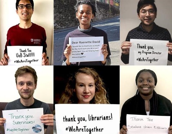 students hold up banners thanking university staff 