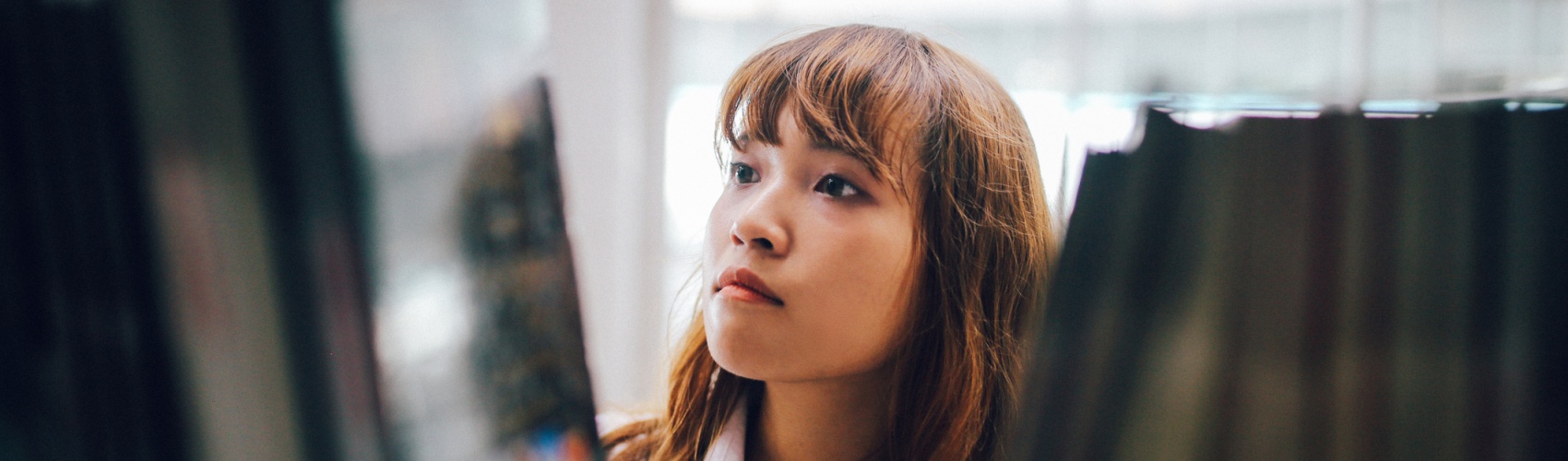 Young Asian student searching for books in the campus library