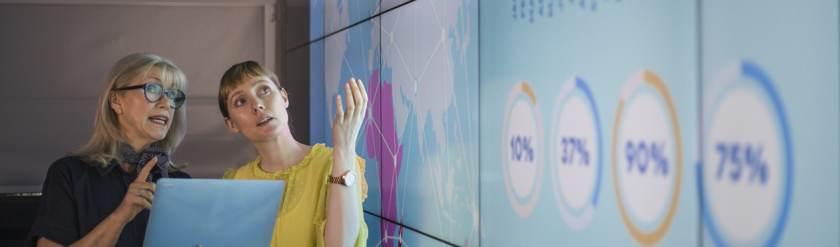 Businesswomen Discussing Ideas Against an Information Wall