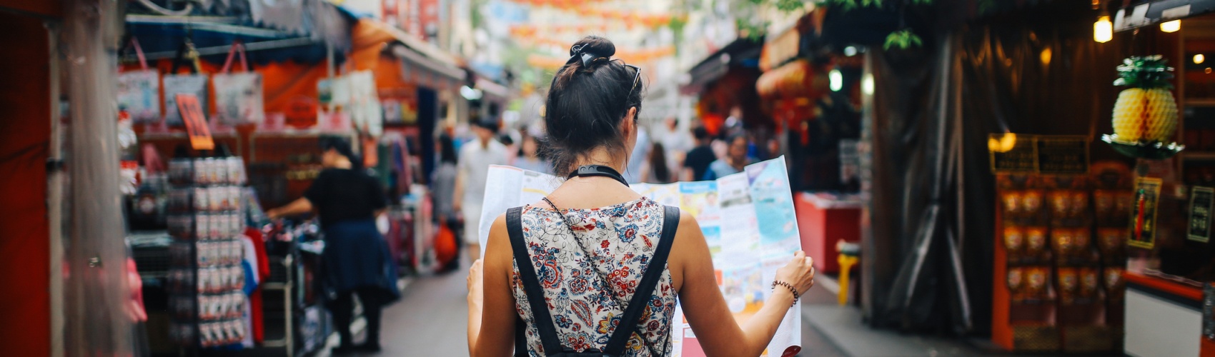 young solo traveler woman in Singapore street market checking the map