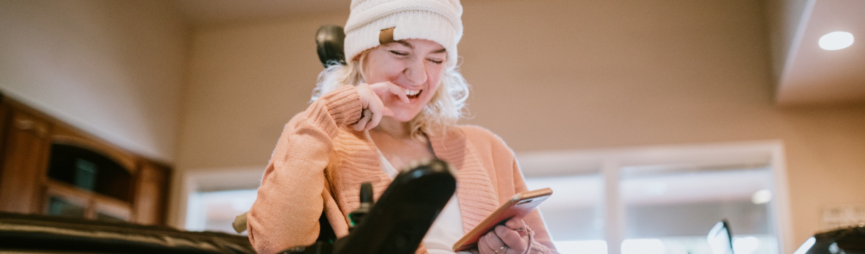 Cheerful Woman In Wheelchair on Smartphone At Home