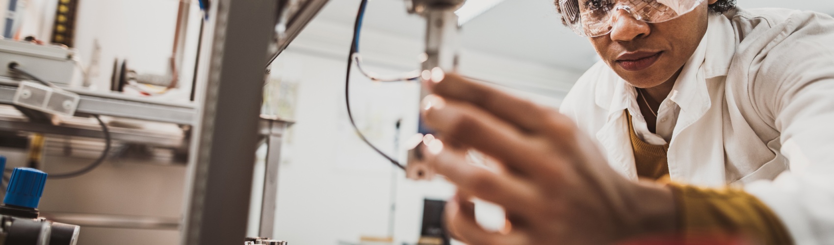 Black female engineer working on industrial machine in a laboratory