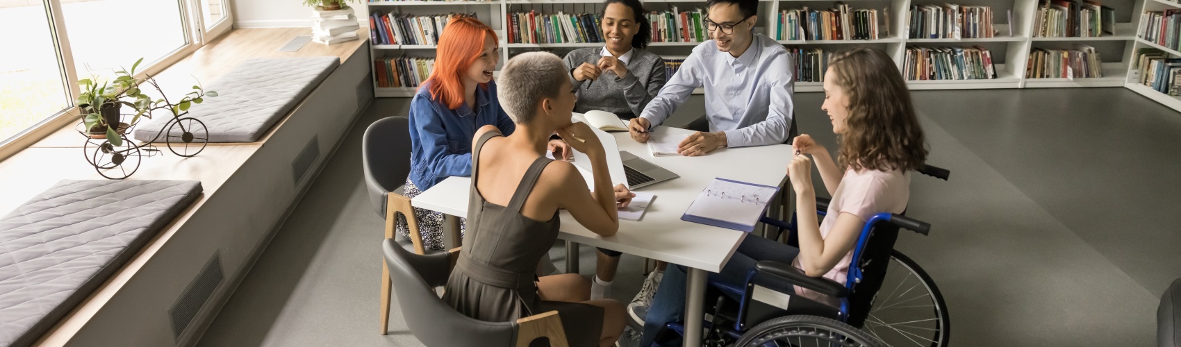 Diverse group of students studying together around a table in a library