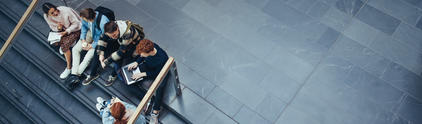 A group of five students sat on a staircase conversing and studying.