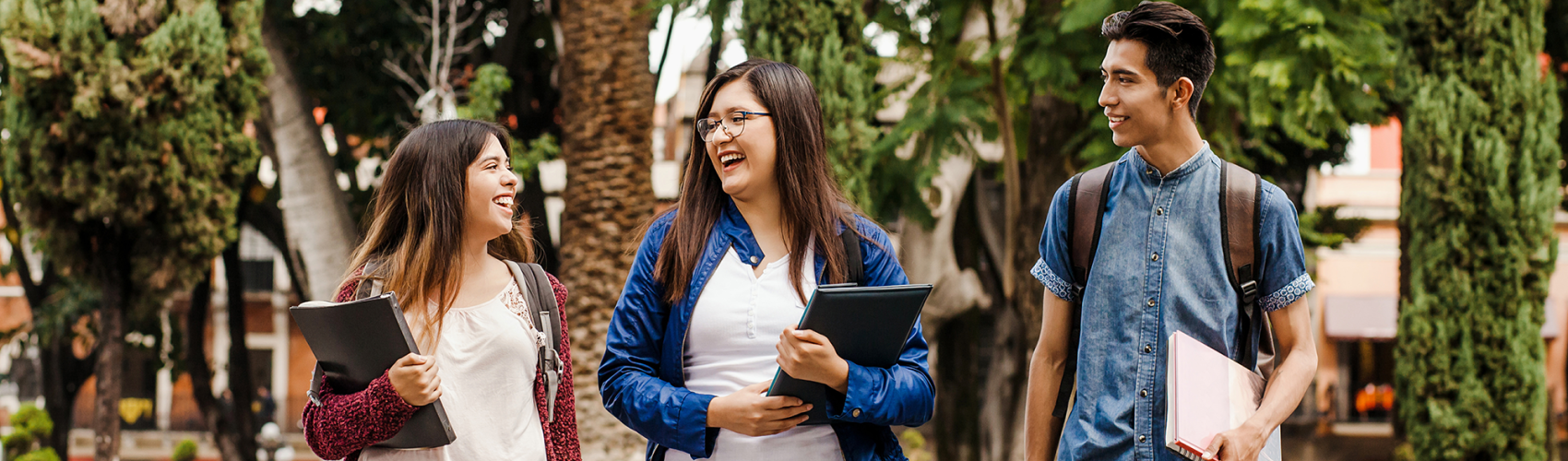 Three students walk across a campus 