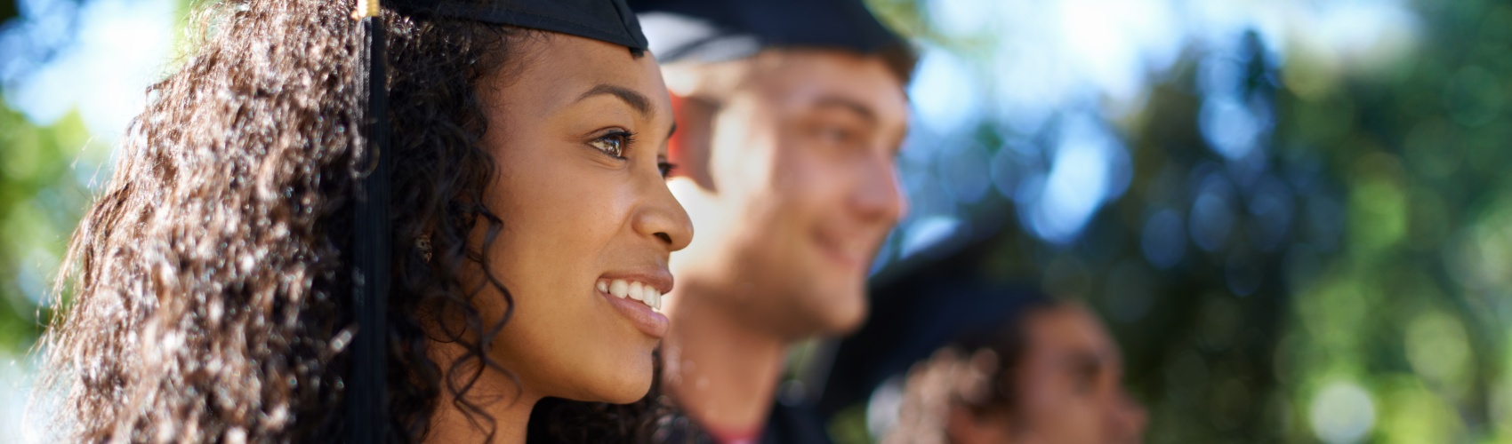 Three students smiling at their graduation outside