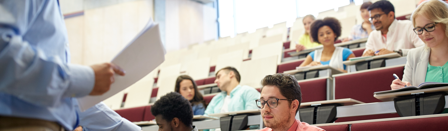 A lecturer hands back an essay to a student in a lecture hall