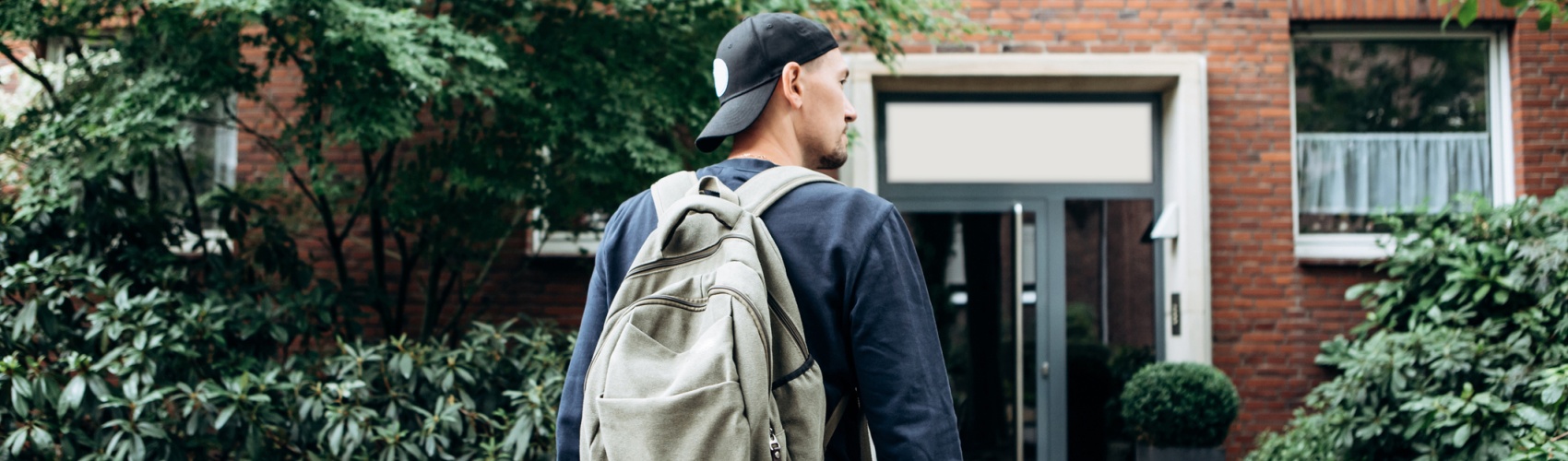 Student wearing backpack returning home to flat