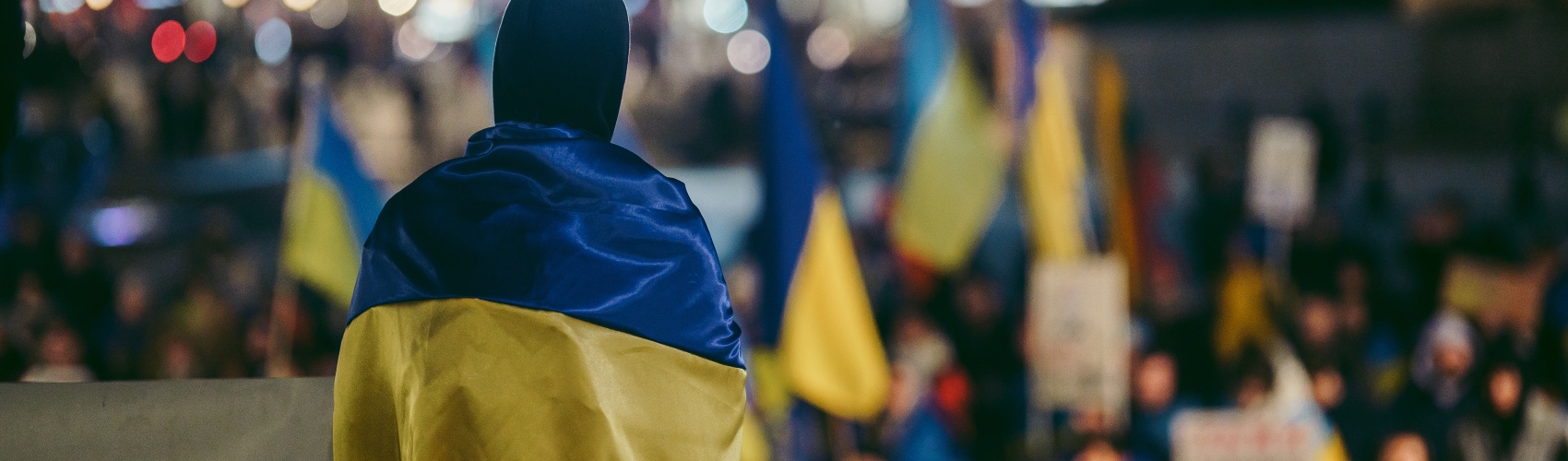 man wrapped in ukraine flag stands in protest