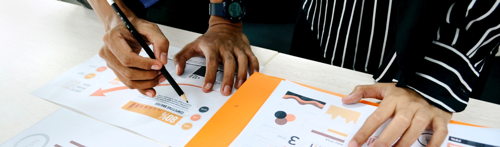 Two people with paper and pencil working with charts and figures