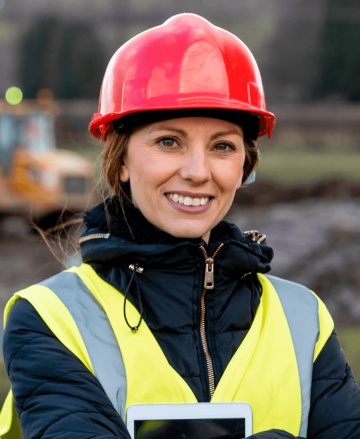 Woman with red hard hat smiling and looking directly at camera.