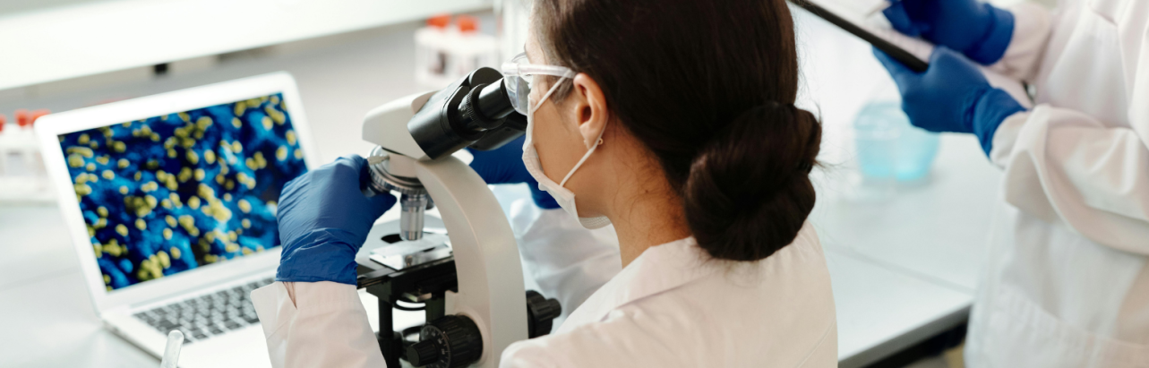 woman looking into a microscope in a lab.