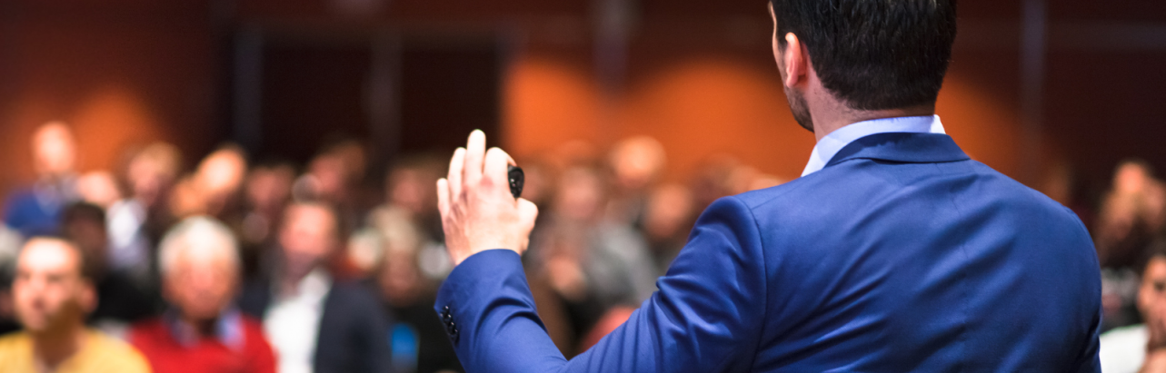 A speaker on stage presenting to the audience
