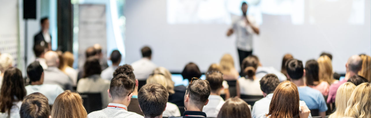 A speaker on stage presenting to the audience