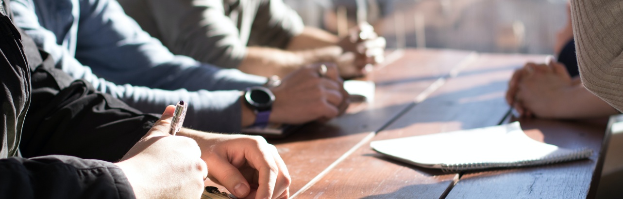 Four people taking notes during a meeting