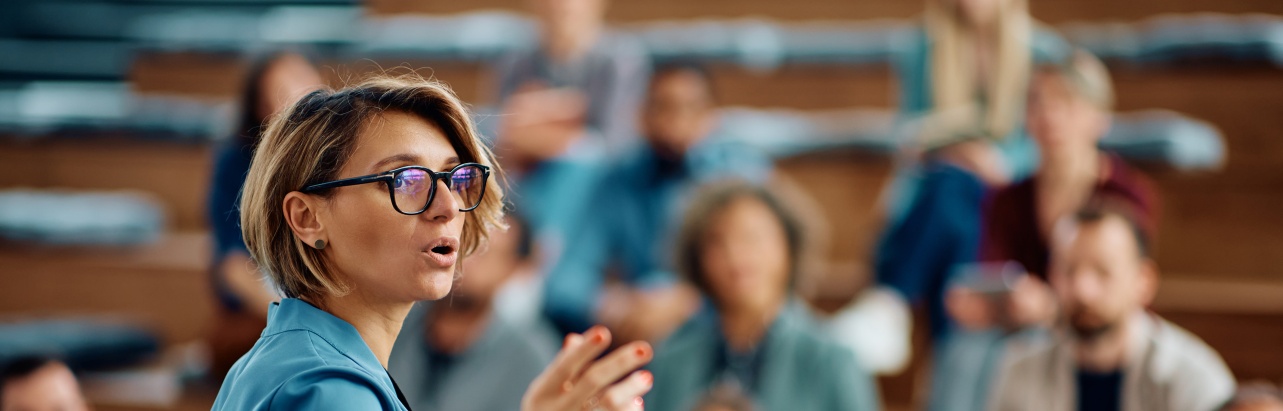 A speaker engages students in a busy lecture hall