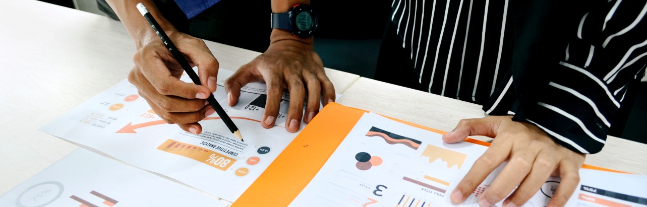 Two people with paper and pencil working with charts and figures
