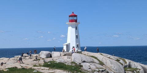 Lighthouse at Peggy's Cove, Nova Scotia, featuring rocks in the foreground and deep blue sea and sky in the background