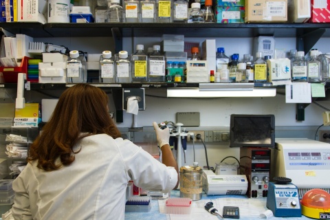 A female researcher works in a lab with stacked shelves 