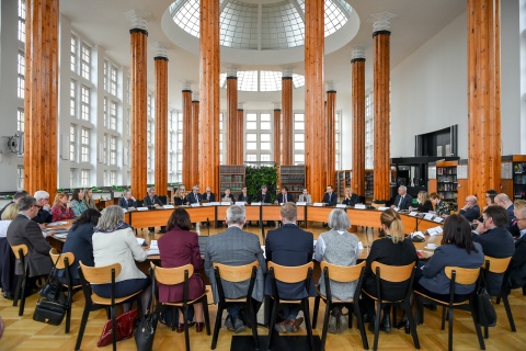 A large number of delegates attend a roundtable session, seated in a circle.