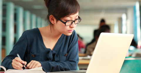 A female asian student sits in a library focussing on work