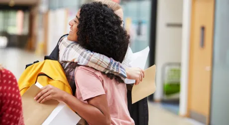 Two high school students embrace over their exam results